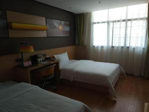 ein Hotelzimmer mit zwei Betten und einem Schreibtisch in der Unterkunft IU Hotels·Anshun Nanma Square in Anshun