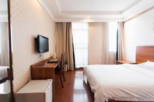 una camera d'albergo con un letto e una scrivania con una televisione di GreenTree Inn Changshu South HaiYu Road Pedestrian Street Business Hotel a Suzhou