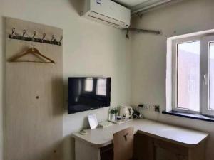 a room with a desk and a tv on the wall at 7 Days Inn Hami Baofeng Market in Qumul +145 photos