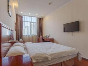 una camera da letto con un letto grande e una TV a schermo piatto di GreenTree Inn Hefei Huangshan Road Business Hotel a Hefei Altre 100 foto
