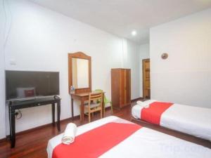 une chambre avec deux lits, un bureau et un miroir dans l'établissement OYO 89537 Fairy Garden Resort, à Kampong Kinasaraban