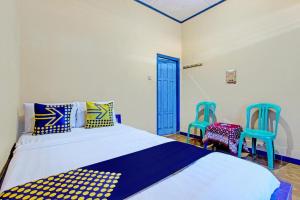 a bedroom with a bed and two blue chairs at SPOT ON 93596 Pondok Wisata Pesona Asri in Kaliurang
