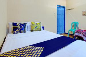 a bedroom with a bed with blue and yellow pillows at SPOT ON 93596 Pondok Wisata Pesona Asri in Kaliurang +36 photos
