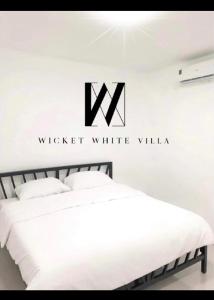 two beds in a white room with a sign on the wall at WICKET WHITE VILLA in Ratchaburi