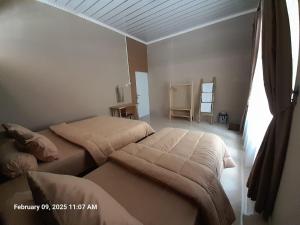 Un dormitorio con dos camas y una ventana. en Griya Al Mukmin Guesthouse Syariah, en Solo