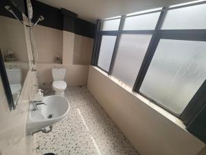 a bathroom with a sink and a toilet and a window at Destiny House Hostel in Hat Yai
