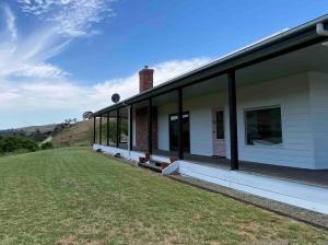 a white house with a grass field next to it at Livingstone-Omeo Hideaway in Omeo