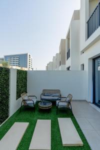 a patio with two chairs and a table on a building at Nasma Luxury Stays - Opulent Family Escape in Marbella RAK in Ras al Khaimah