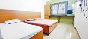 a bedroom with two beds and a window in it at Elite Residency in Taliparamba
