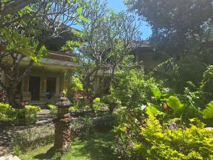 a woman standing in the garden of a house at Rambutan Hotel in Lovina
