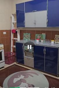 une cuisine avec des armoires bleues et un tapis de singe dans l'établissement ايجار مفروش بارقى كمبوند بالشيخ زايد, à Sheikh Zayed