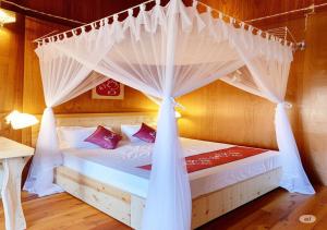 a bed with a canopy in a room at Pu Luong Homestay & Tours in Hương Bá Thước