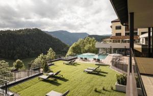 ein Balkon eines Gebäudes mit einem Hof und einem Pool in der Unterkunft Hotel Alpenflora in Kastelruth