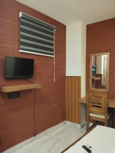 a living room with a television on a wall at Anantha Guest House in Trivandrum +41 photos