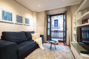 a living room with a blue couch and a television at Avientu By Silastur in Gijón
