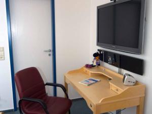 a room with a desk with a television and a chair at Separatè im Haus Carmen in Schrebitz