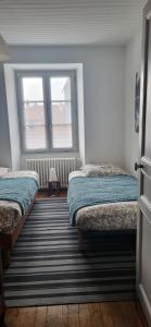 a bedroom with two beds and a window at La Maison de Claire in Flavigny-sur-Ozerain