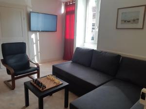 a living room with a black couch and a chair at La Maison de Claire in Flavigny-sur-Ozerain