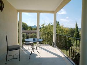 Un patio con una mesa y sillas en un balcón. en Lou pastre, en Saint-Rémy-de-Provence