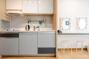 a kitchen with white cabinets and stools at JSM Studio Hongdae in Seoul