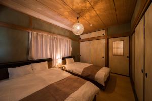 een slaapkamer met twee bedden en een hanglamp bij 別府温泉 小倉の湯 in Beppu