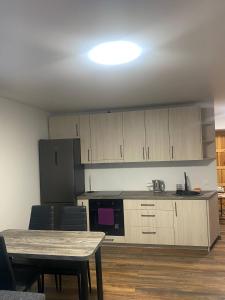 a kitchen with wooden cabinets and a table with chairs at Butas Čiurlionio gatvėje in Pakopi +3 photos