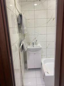 a white bathroom with a sink and a tub at Butas Čiurlionio gatvėje in Pakopi