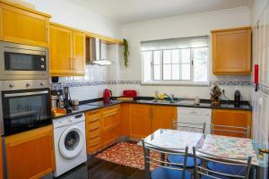 een keuken met houten kasten en een wasmachine en droger bij Rosária Flat in Santa Cruz +13 foto's