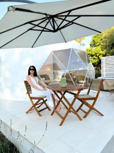 CariaLa Fontana Glamping的坐在桌子下伞下的女人