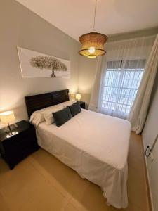 Un dormitorio con una gran cama blanca con dos almohadas. en Apartamento La Rosa, en El Puerto de Santa María