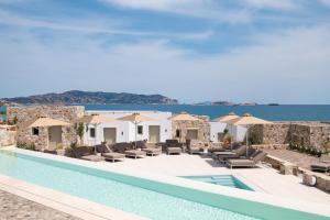 a pool with chairs and umbrellas next to the ocean at Espera Suites in Kimolos