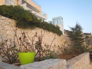 a stone wall with a green pot in front of a building at Viva B&B in Anavyssos