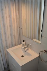 Un baño con un lavabo blanco y un espejo. en Apartamento La Rosa, en El Puerto de Santa María 10 fotos más