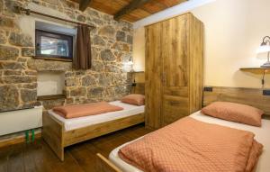 two beds in a room with a stone wall at Casa Antica - Storia Verde Opatija in Veprinac +26 photos