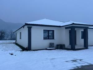 a small white house with snow on the ground at Vila Selena in Onceşti