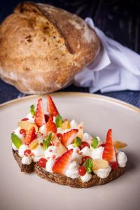 a piece of toast with fruit on a plate with a loaf of bread at Der Schlosswirt zu Anif - Biedermeierhotel und Restaurant in Anif +134 photos