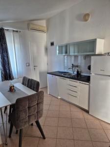 a kitchen with a table and a white refrigerator at Apartments Neda in Primošten +44 photos