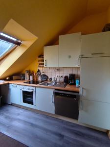 a kitchen with white cabinets and a sink and a stove at Gemütliche, ruhige Dachwohnung in Lütow für bis zu 4 Personen in Lütow