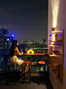 Una mujer sentada en un bar en la azotea de un edificio. en The Establishment - Menara Teguh Bangsar, en Kuala Lumpur