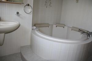 a white bathroom with a tub and a sink at Plazzetta 23 in Sent
