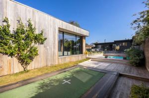 Quay-Walk to beach Gas Heated Pool, Spa, Trampoline في بليرغوري: منزل خشبي أمامه حديقة خضراء