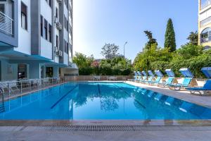 a swimming pool with lounge chairs and a building at Tunali Apart Hotel in Antalya