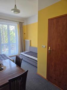 a room with a bed and a table and a door at WILLA "SZCZĘSNA" in Piwniczna