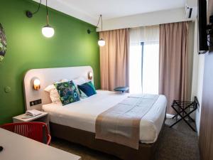 カイエンヌにあるIbis Styles Cayenne Centre Amazoniaの緑の壁のベッドルーム1室(大型ベッド1台付)