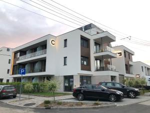 two cars parked in a parking lot in front of a building at LigetResidence Apartman in Fonyód