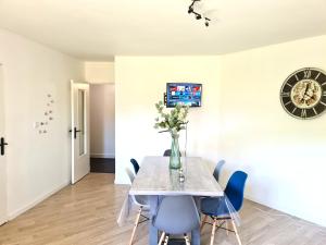 a dining room with a table and chairs and a clock at Dans les Nuages - Entrée autonome - Mulhouse Centre in Mulhouse