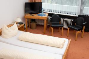 a room with a bed and two chairs and a desk at Landhotel Westerwald in Ehlscheid