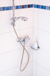 a shower head in a bathroom with white tiles at Landhotel Westerwald in Ehlscheid