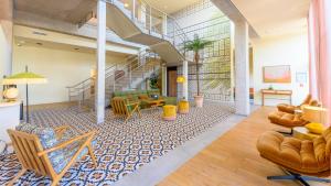 a living room with a staircase and a couch and chairs at Kyriad Prestige Compiègne Hotel & Spa in Compiègne