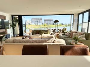 a living room with couches and a large window at Still Waters - Luxury Lakeside Retreat with Hot Tub in Warmwell